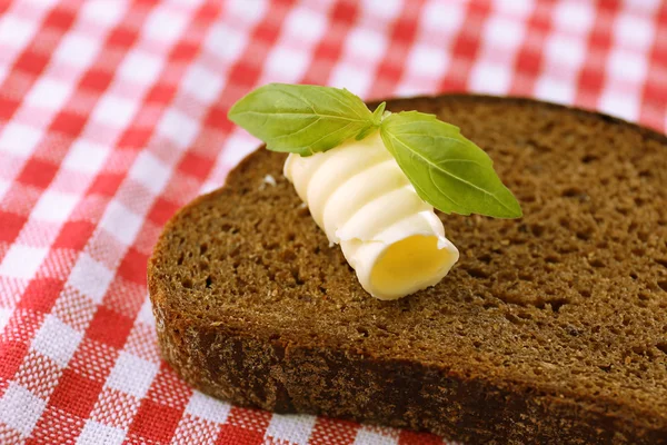 Rebanada de pan de centeno con mantequilla, sobre mantel —  Fotos de Stock