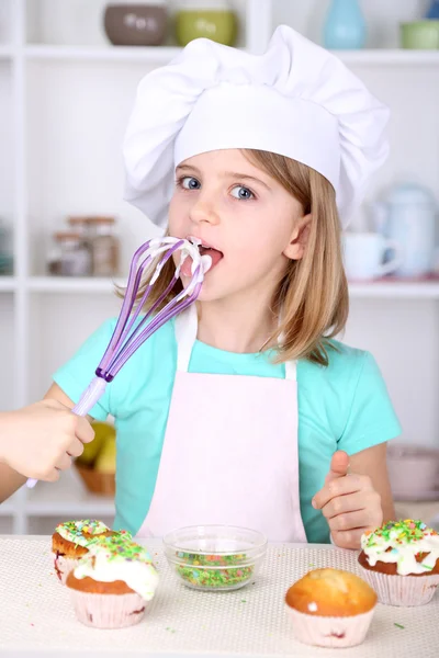 Kleines Mädchen isst Creme in der Küche zu Hause — Stockfoto