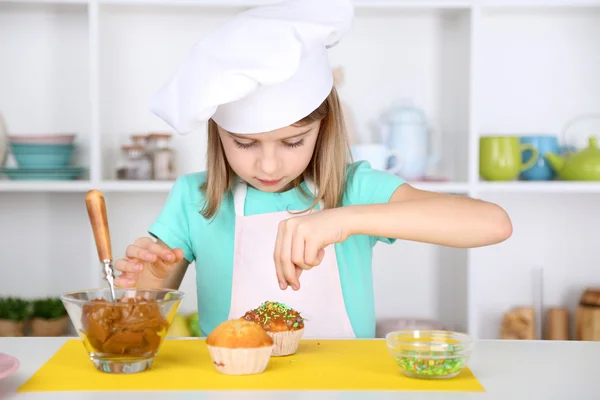 Klein meisje cupcakes in keuken thuis verfraaien — Stockfoto