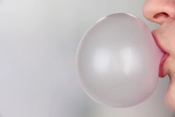 Человек делает пузырь с жевательной резинкой на ярком фоне — стоковое фото