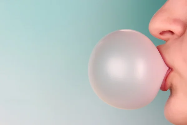 Человек делает пузырь с жевательной резинкой на ярком фоне — стоковое фото
