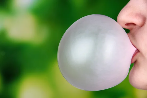 Osoba dělá bubliny s žvýkačky na světlé pozadí — Stock fotografie