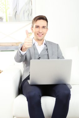 genç işadamı evde kanepede dizüstü kullanarak