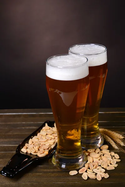 Biergläser mit Imbiss auf Tisch vor dunklem Hintergrund — Stockfoto