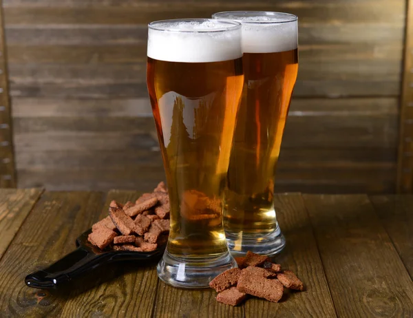 Glazen bier met snack op tafel op houten achtergrond — Stockfoto