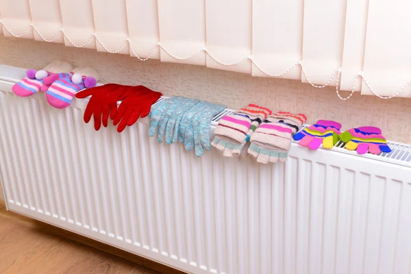 Knitted gloves drying on heating radiator — Stock Photo, Image