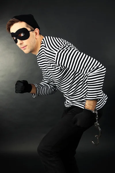 Thief with handcuffs on dark background — Stock Photo, Image