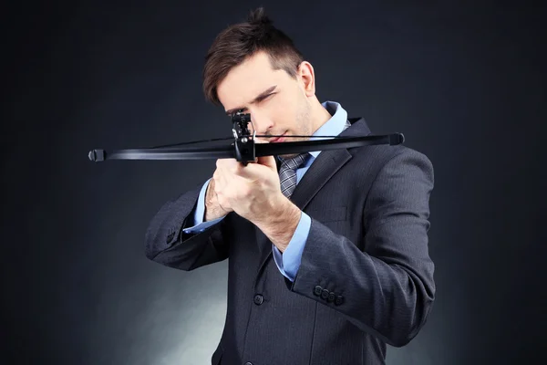 Joven empresario con ballesta, sobre fondo oscuro —  Fotos de Stock