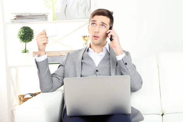 Giovane uomo d'affari che utilizza il computer portatile sul divano a casa — Foto Stock