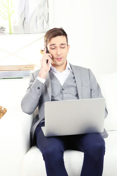 Giovane uomo d'affari che utilizza il computer portatile sul divano a casa — Foto Stock