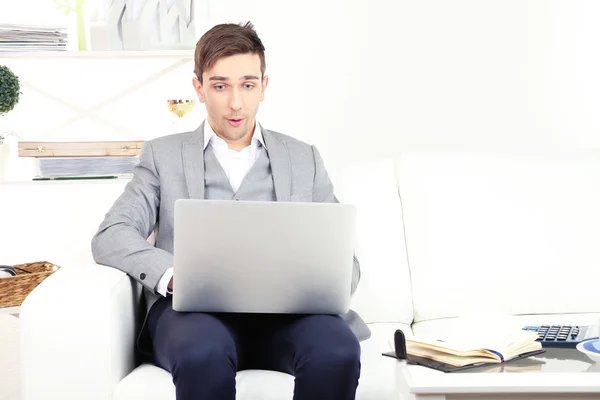 Молодий бізнесмен використовує ноутбук на дивані вдома — стокове фото