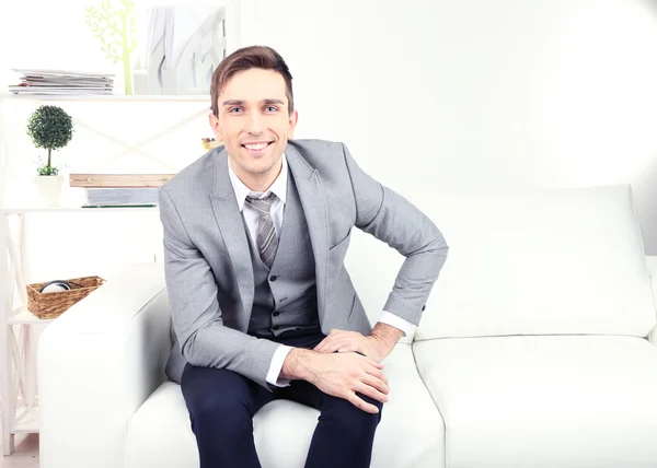 Eleganter junger Geschäftsmann sitzt gemütlich auf dem Sofa, zu Hause — Stockfoto
