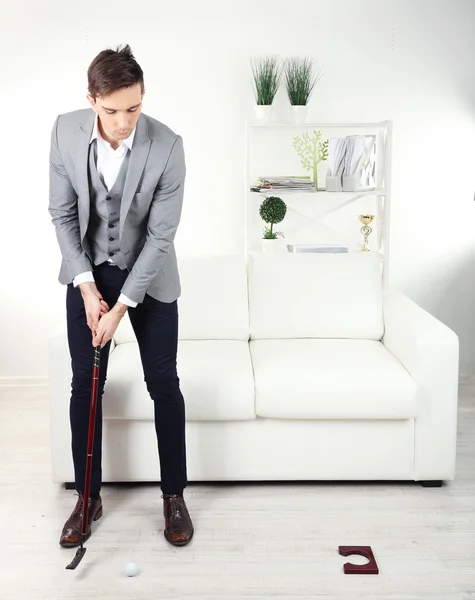 Elegante joven empresario jugando mini golf en casa —  Fotos de Stock