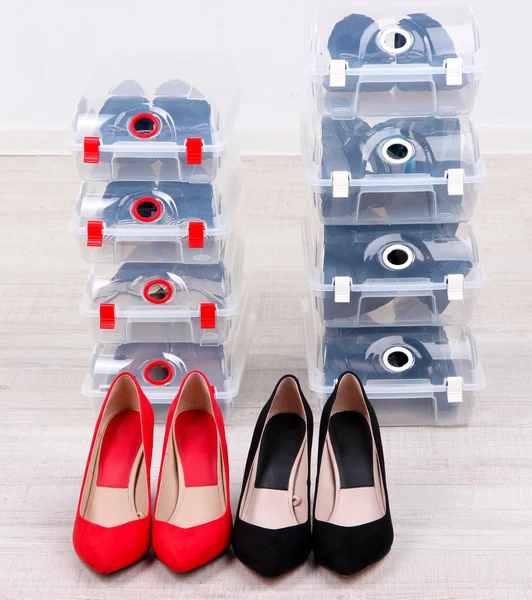 Zapatos en cajas de plástico y zapatos femeninos en el piso en la habitación — Foto de Stock