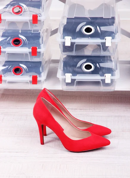 Zapatos en cajas de plástico y zapatos femeninos en el piso en la habitación —  Fotos de Stock