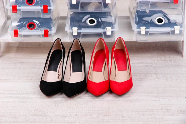 Zapatos en cajas de plástico y zapatos femeninos en el piso en la habitación — Foto de Stock