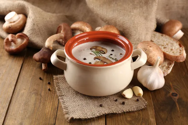Mushroom soup in pot, on wooden table, on sackcloth background — Stock Photo, Image