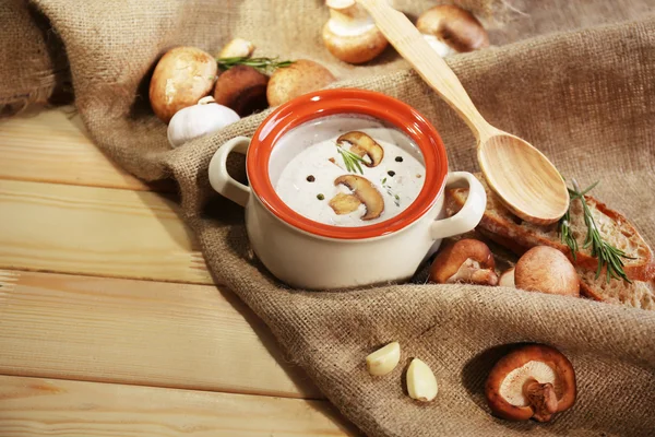 Mushroom soup in pot,on napkin, on wooden background — Stock Photo, Image