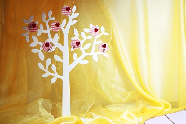 Декоративная елка с декоративными сердцами, на деревянном столе на фоне цветной ткани — стоковое фото