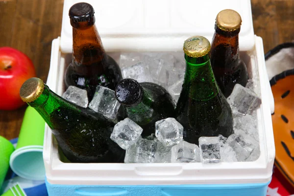 Pecho de hielo lleno de bebidas en botellas en servilleta de color, sobre fondo de madera — Foto de Stock