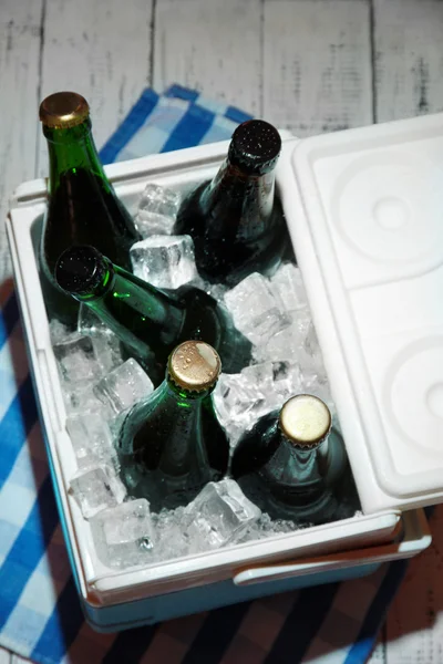 Pecho de hielo lleno de bebidas en botellas en servilleta de color, sobre fondo de madera — Foto de Stock