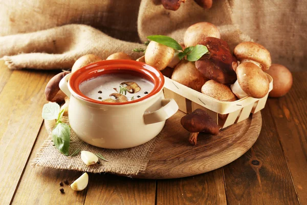 Composition with mushroom soup in pot, fresh and dried mushrooms, on wooden table, on sackcloth background — Stock Image Composition with mushroom soup in pot, fresh and dried mushrooms, on wooden table, on sackcloth background Stock Image