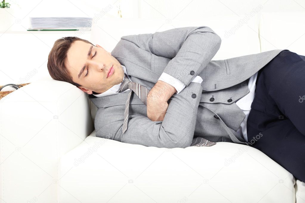 Elegant young businessman sleeping on sofa, at home