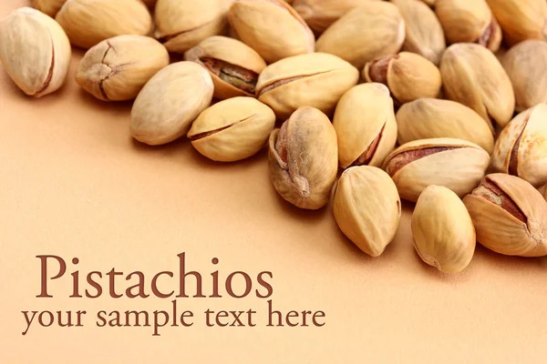 Tasty pistachio nuts, on beige background — Stock Photo, Image