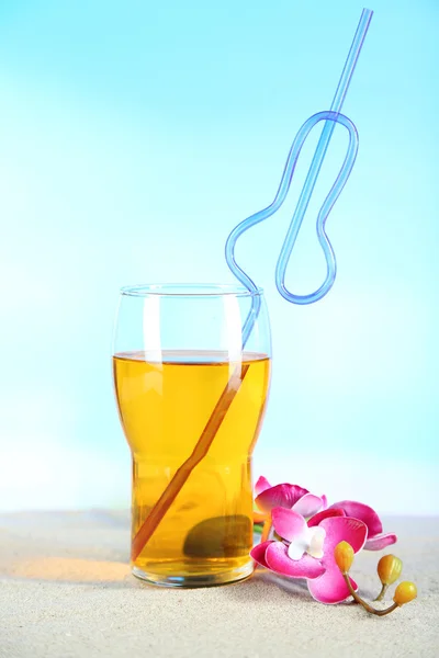 Glass of cocktail, on sand, on bright background — Stock Photo, Image