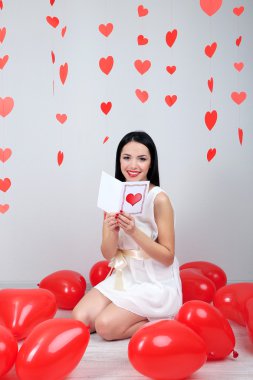 çekici bir genç kadın bir şekilde dekore edilmiş oda kartı Sevgililer gününde okuyun.