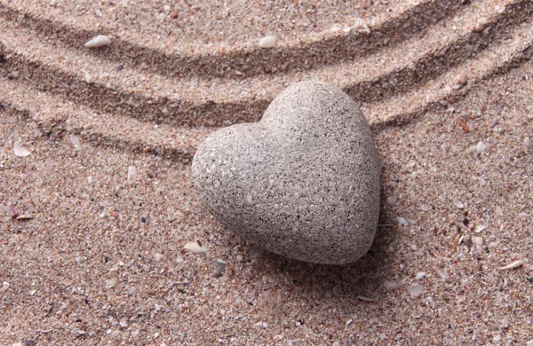 Szary kamień zen w kształcie serca, na tle piasek — Zdjęcie stockowe