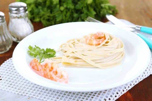 Pasta con gambas sobre plato blanco, sobre fondo de madera —  Fotos de Stock