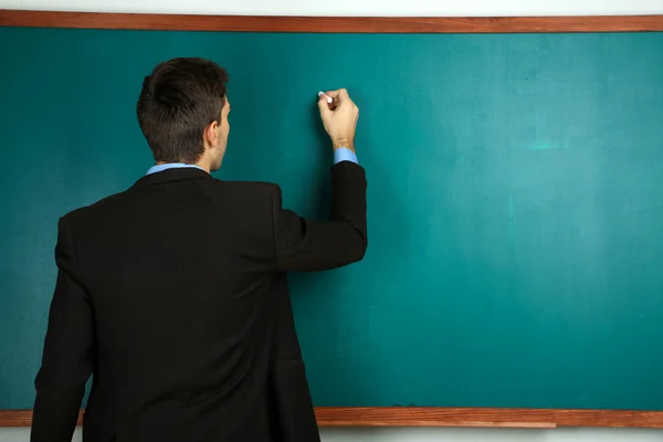 Jonge leraar in de buurt van schoolbord in school klas — Stockfoto