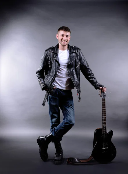 Νεαρός μουσικός με κιθάρα σε σκούρο χρώμα του φόντο — Φωτογραφία Αρχείου