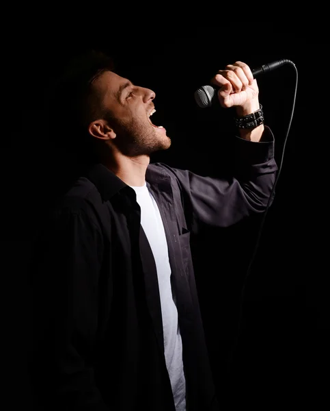 Joven músico cantando, sobre fondo gris — Foto de Stock