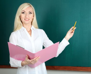 öğretmen sınıfta blackboard yakınındaki klasörle