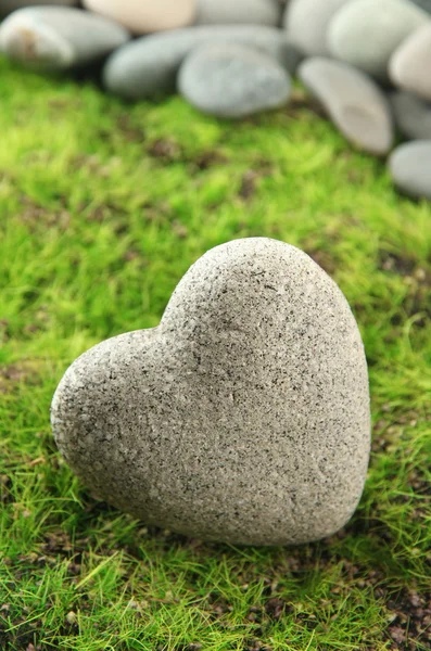 Grå sten i form av hjärta, på gräs bakgrund — Stockfoto