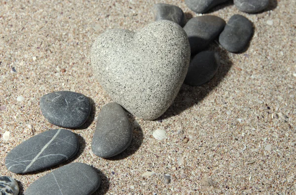Szary kamień w kształcie serca, na tle piasek — Zdjęcie stockowe