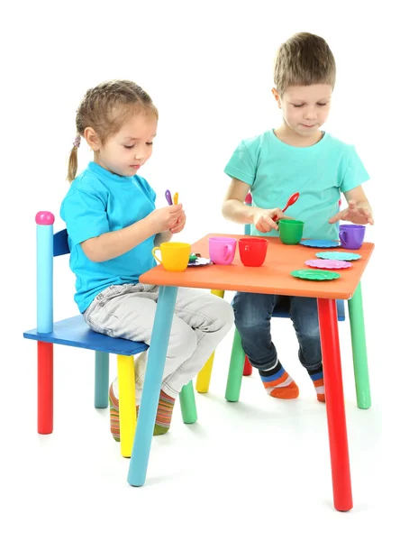 Kleine Kinder spielen mit buntem Geschirr isoliert auf weiß — Stockfoto