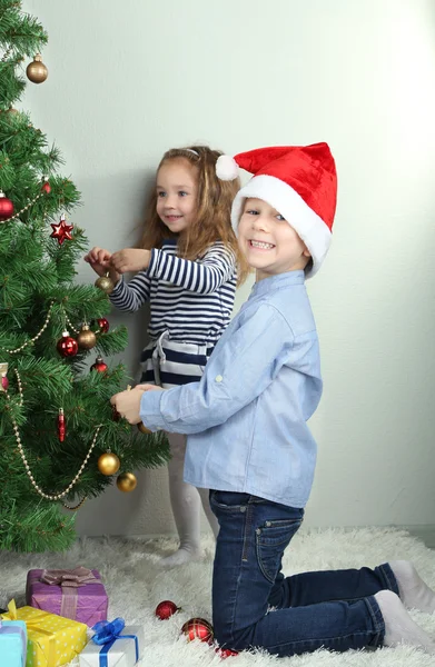 Kinderen versieren kerstboom met kerstballen op kamer — Stockfoto