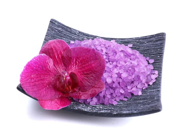 Beautiful blooming orchid flower and heap of sea salt on plate, isolated on white — Stock Photo, Image