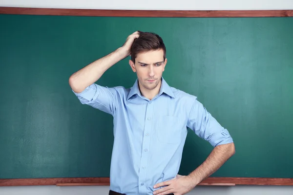 Young teacher near chalkboard in school classroom — Stock Photo, Image