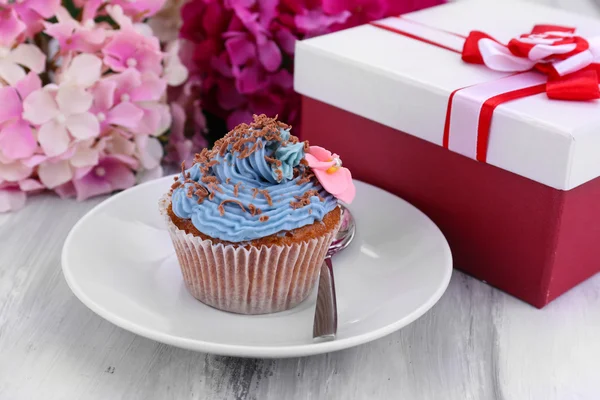 Tasty cupcake with butter cream, on plate, on color wooden background — Stock Photo, Image