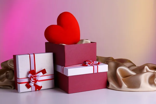 Стек подарункових коробок та декоративного серця на кольоровому фоні — стокове фото