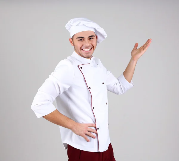 Professionele chef-kok in het witte uniform en hoed, op grijze achtergrond — Stockfoto