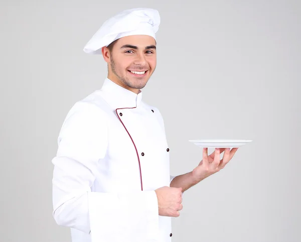 Професійний шеф-кухар у білій формі та капелюсі на сірому фоні — стокове фото