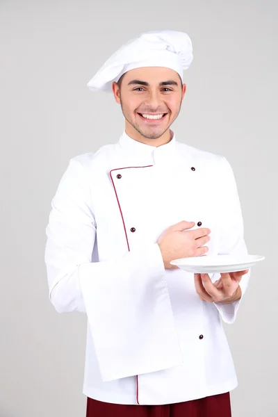Professionel kok i hvid uniform og hat, på grå baggrund - Stock-foto