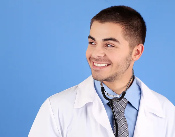 Muž lékař stojící na modrém pozadí — Stock fotografie