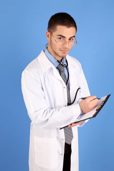 Male Doctor standing with folder, on blue background — Stock Photo, Image