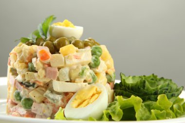 geleneksel Rus salatası olivier, tahta masada gri arka plan üzerinde renkli peçete üzerinde